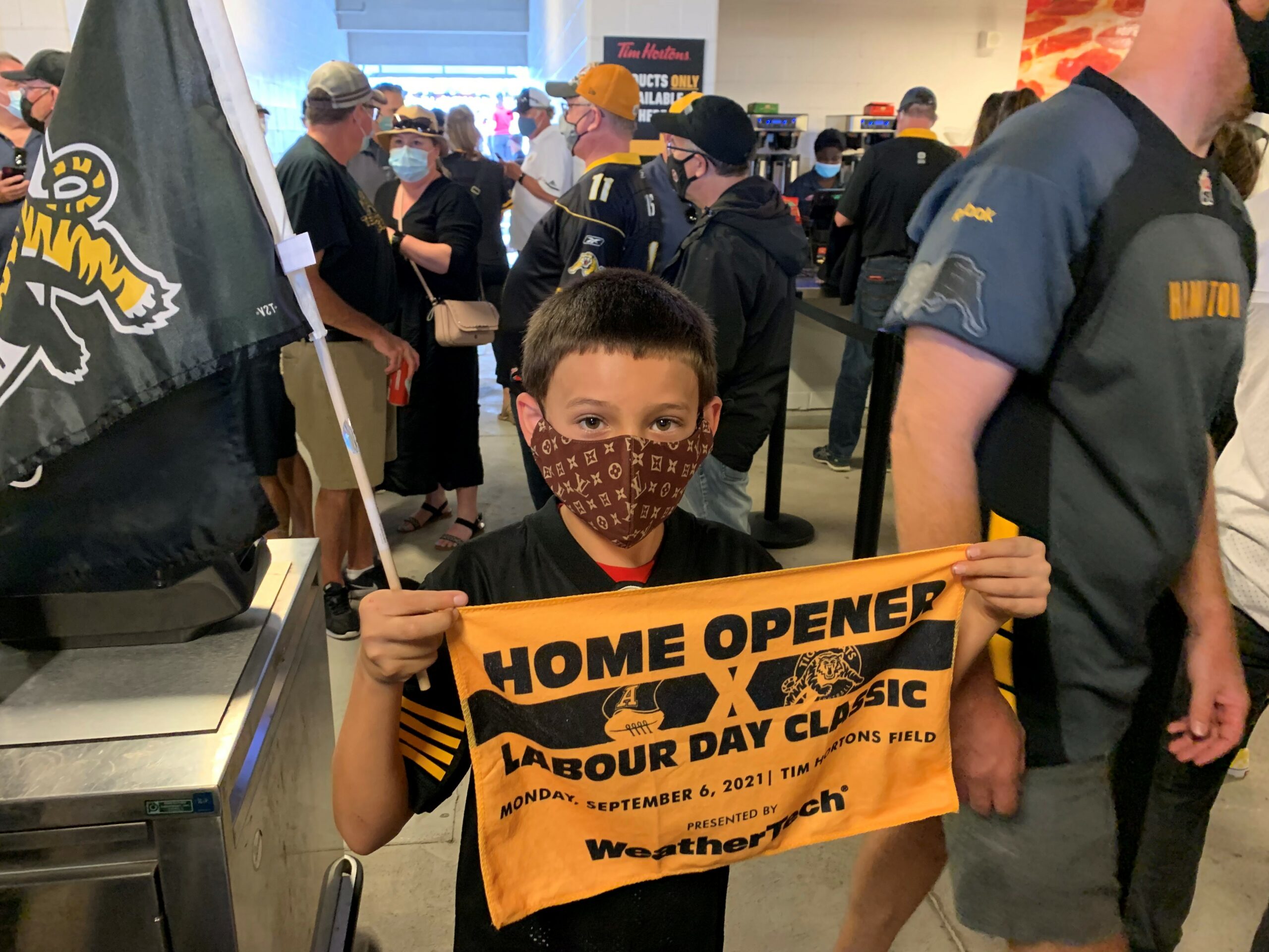 Picture of a young boy at a Hamilton Tiger-Cats football game, in the concourse area.