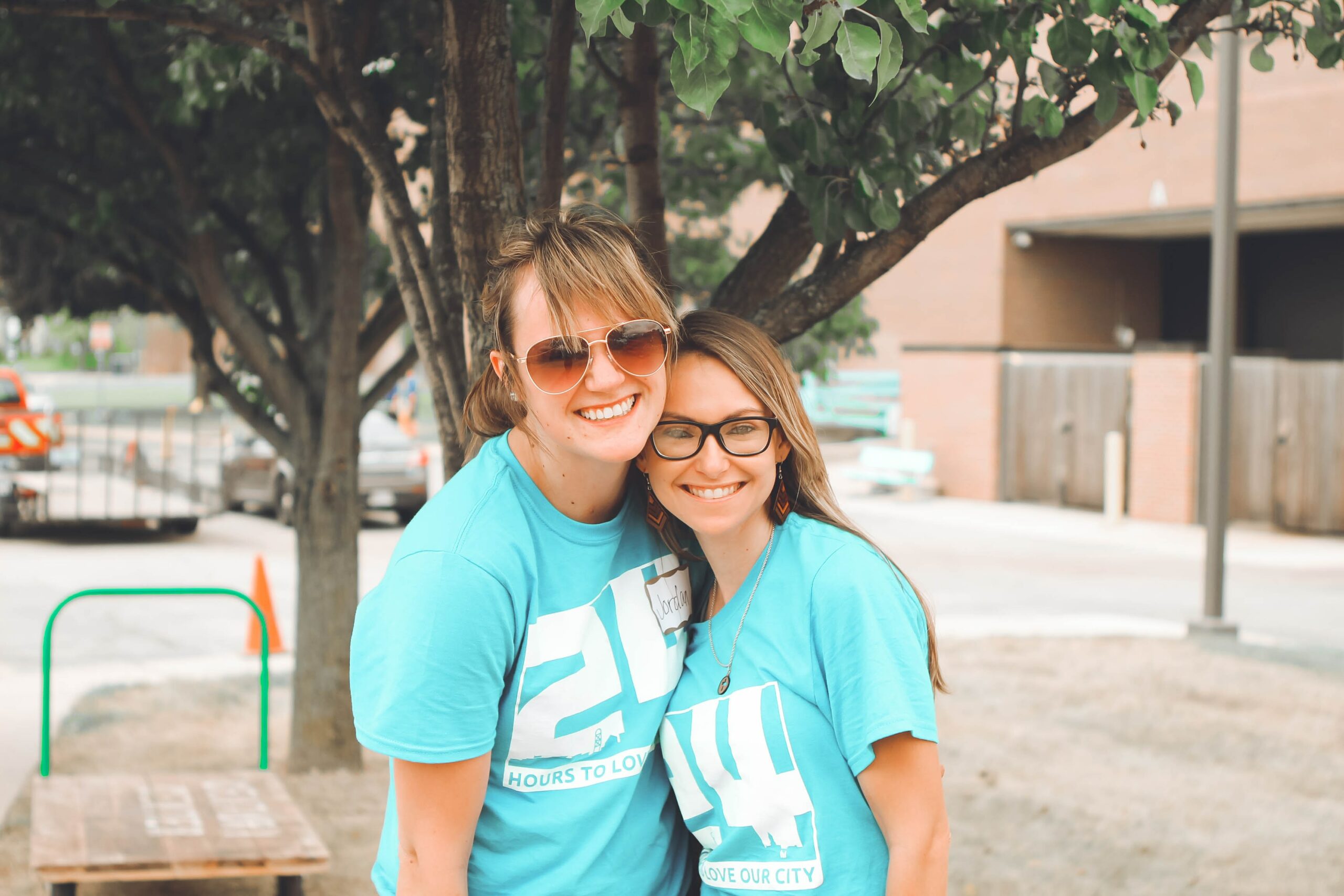 two women embracing each other, wearing blue big brothers big sisters volunteer shirts